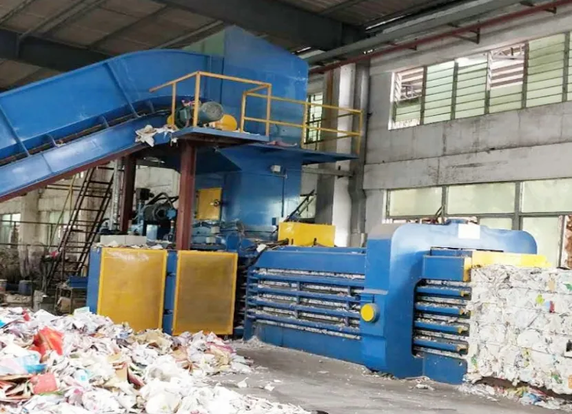 A JENAILV horizontal baling press in a factory workshop, with baled paper stacked beside it