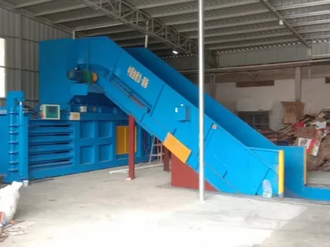 A paper baling line with feed conveyor installed in a workshop